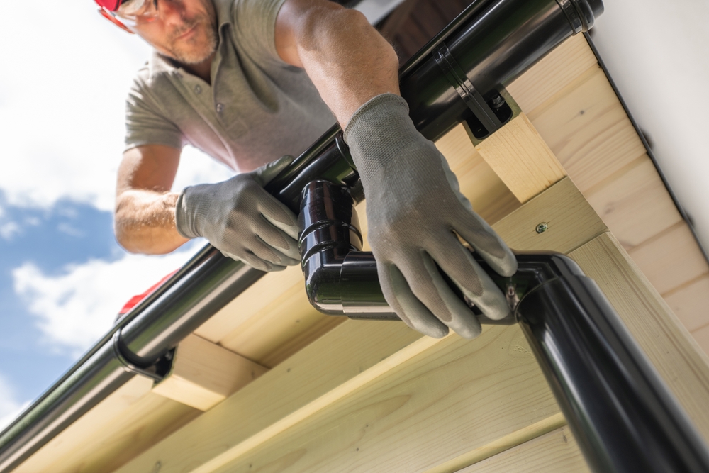 Worker,Installing,Gutter,System,On,Roof